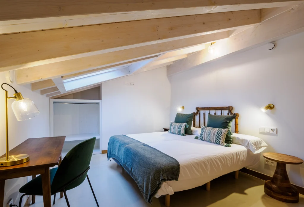 Dormitorio de matrimonio con vigas de madera clara en alojamiento rural