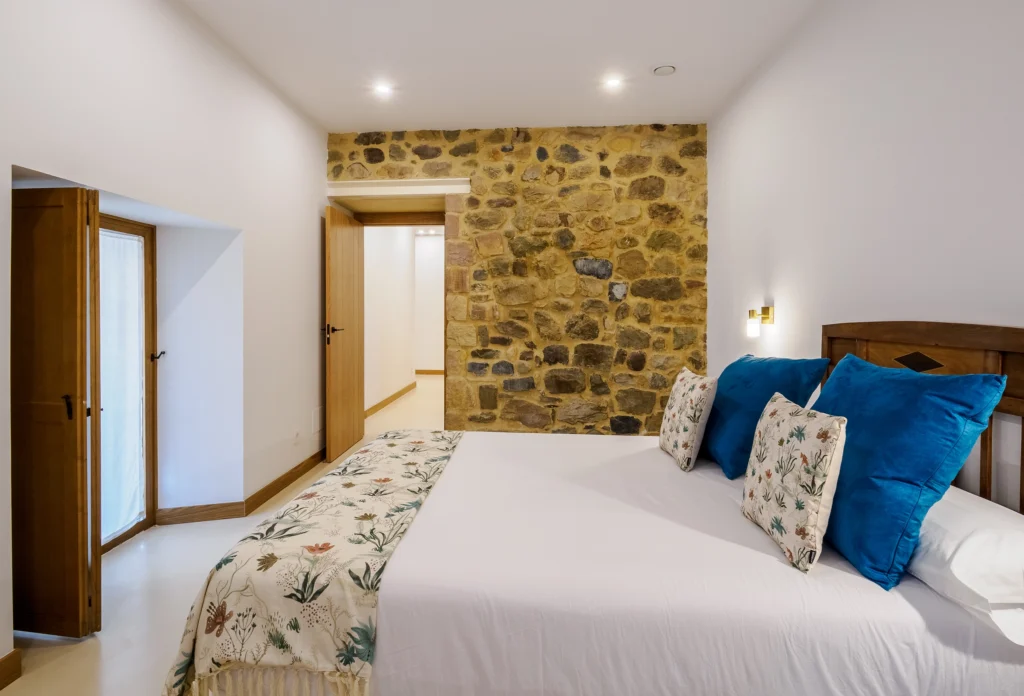 Dormitorio con pared de piedra y ventanas de madera